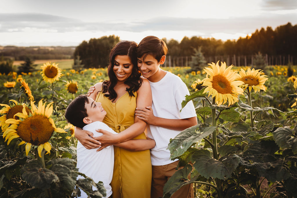 Kara Stephens with her children in a sunflower field.