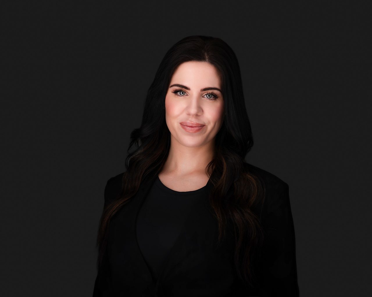 Kara Stephens wearing black against a dark background.