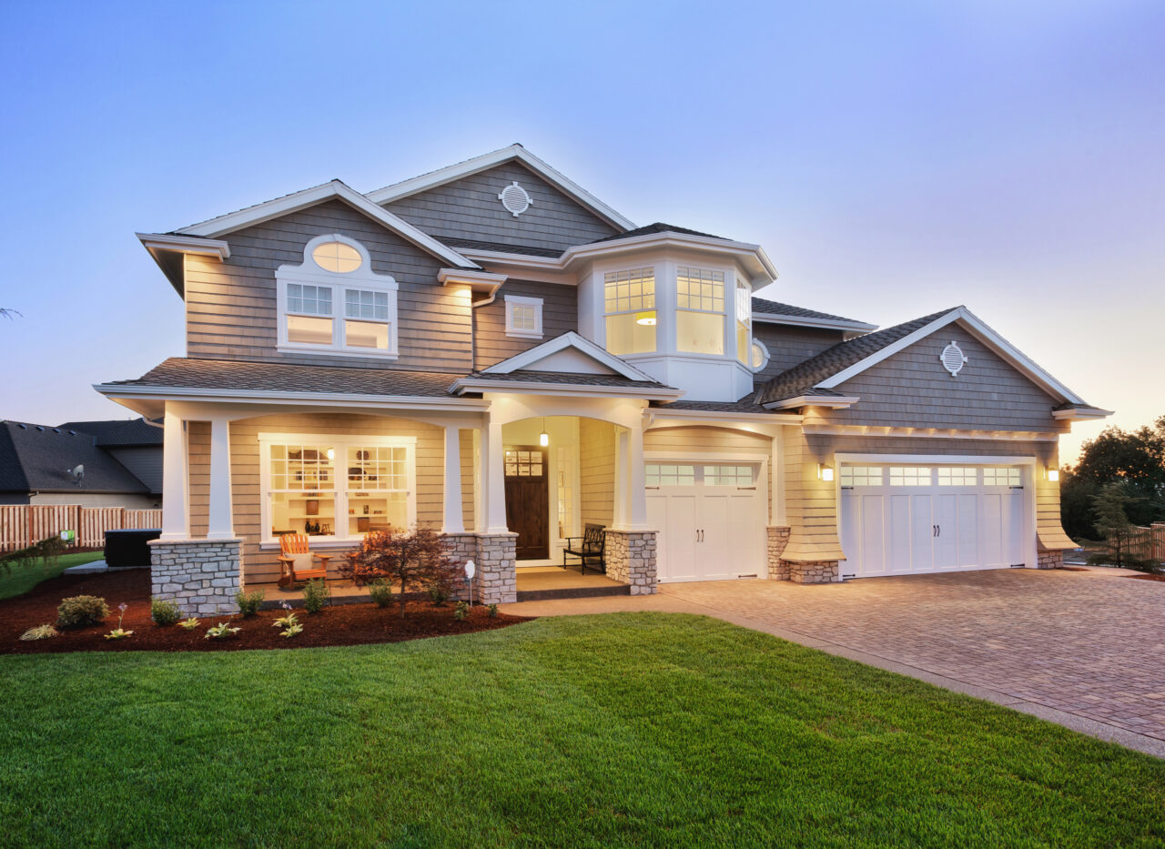 Two-storey suburban home with an illuminated porch and double garage at dusk.